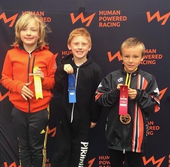 Three children standing next to each other holding medals.