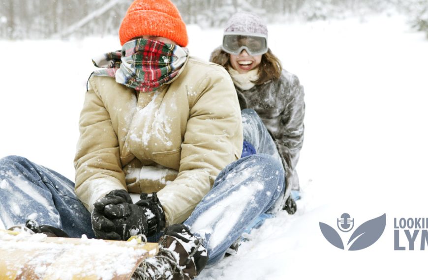 Two people sledding down a snowy hill.