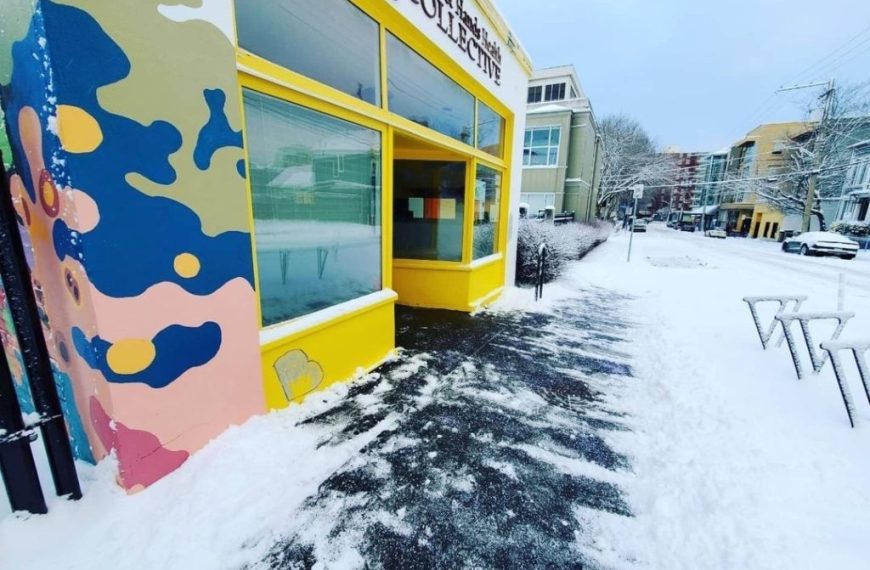 A colorful building with snow on the sidewalk.