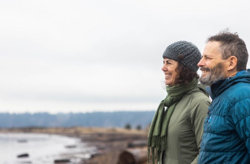 A man and woman are standing next to a body of water.
