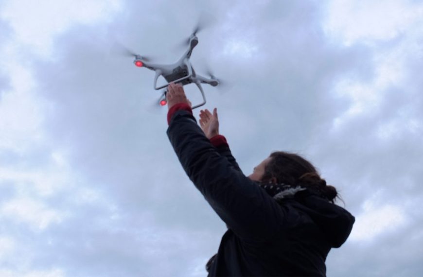 A woman flies a drone in the sky.