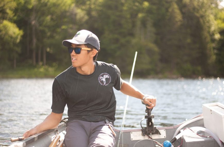 A young man sitting in a boat on a lake.