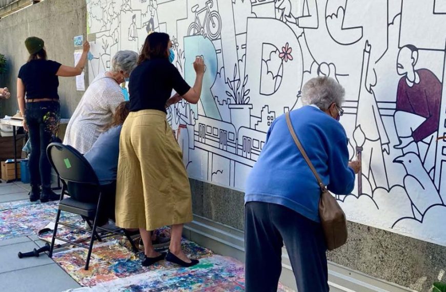 A group of people painting a mural on a wall.