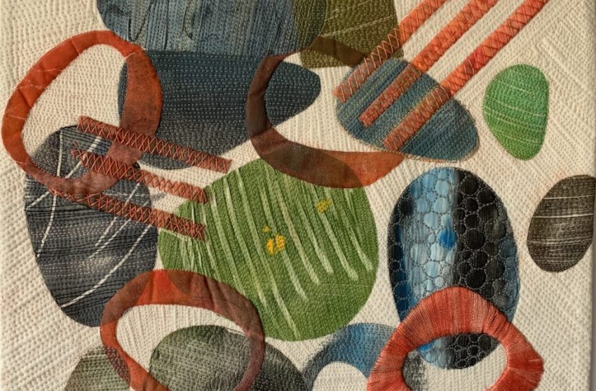 A quilt with various shapes and colors on it.