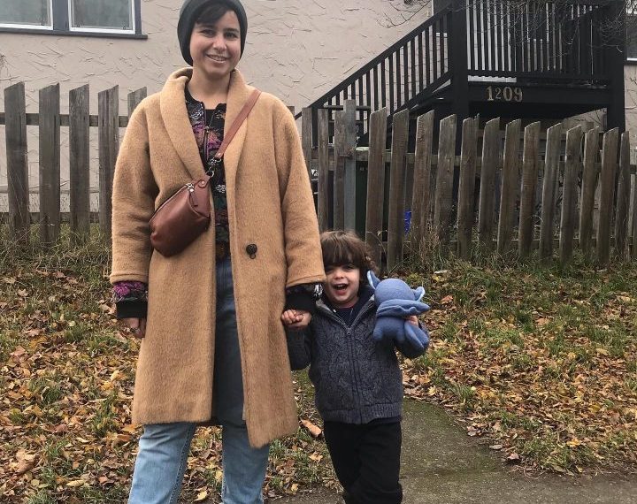 A woman and a child standing in front of a house.