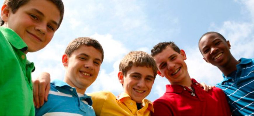 A group of young men are posing in front of a blue sky.