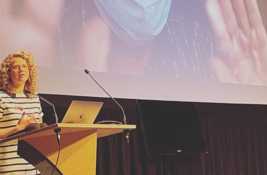 A woman standing at a podium and giving a presentation.