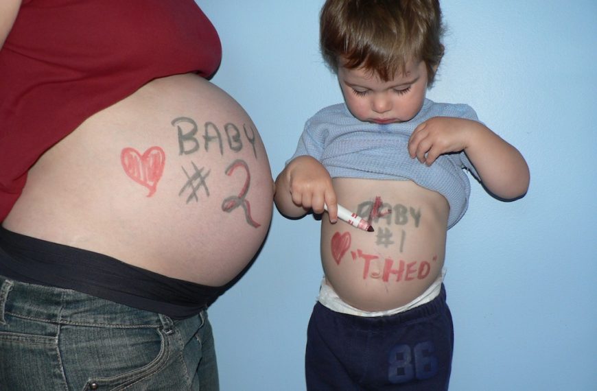 A pregnant woman and a child with writing on their stomachs.