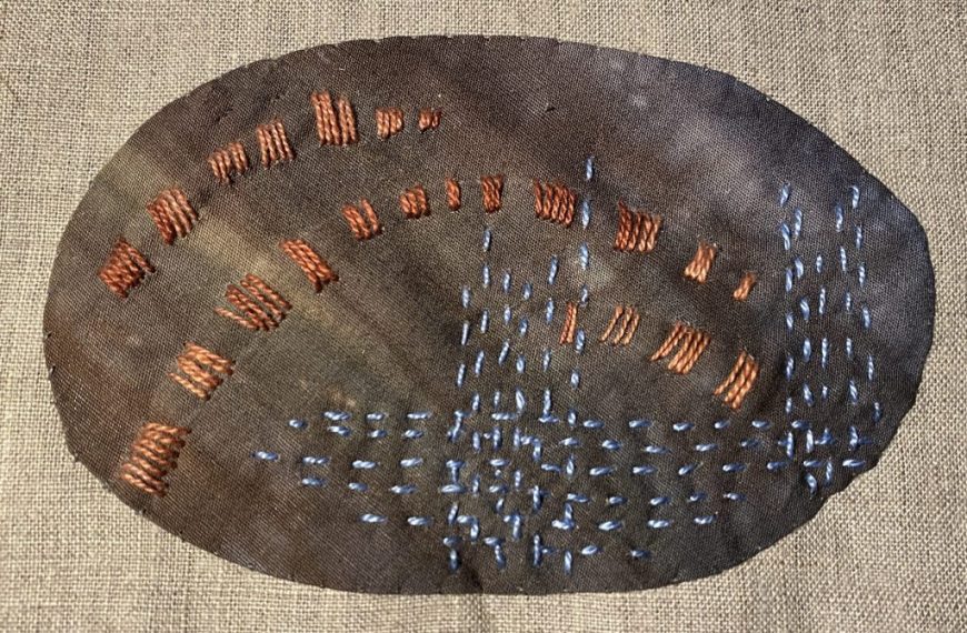 A piece of cloth with threads on it.