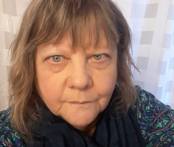 A woman in a blue scarf is taking a selfie.