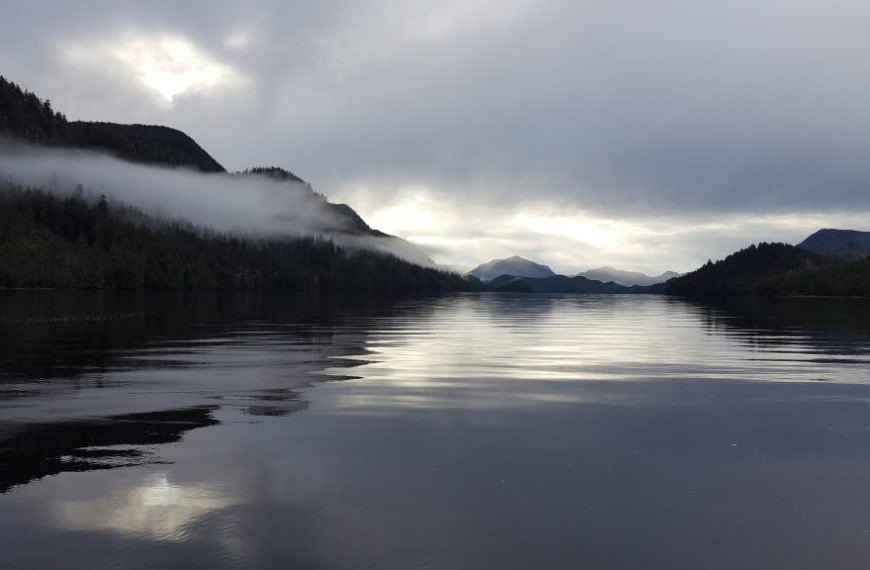 A lake surrounded by mountains and clouds.