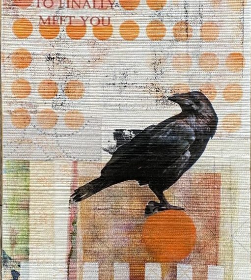 A black crow sits on top of a piece of paper.