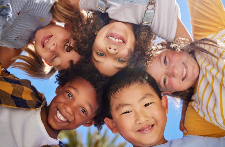 A group of children are standing in a circle and smiling.