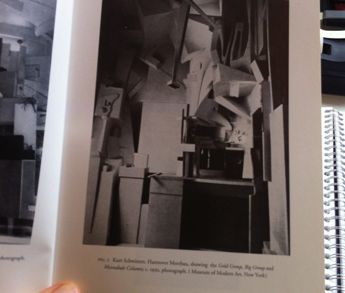 A person is holding a book with a photograph of a room.