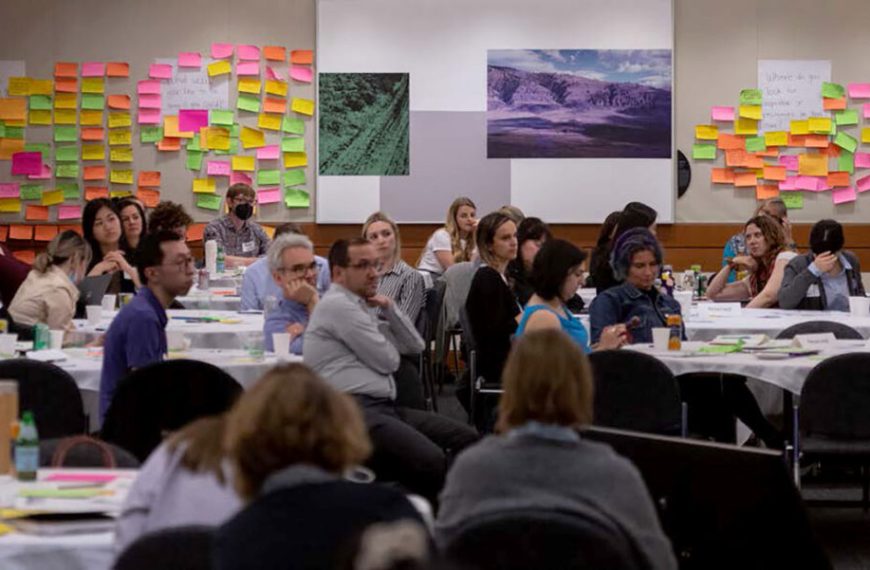 A group of people sitting at tables in a conference room.