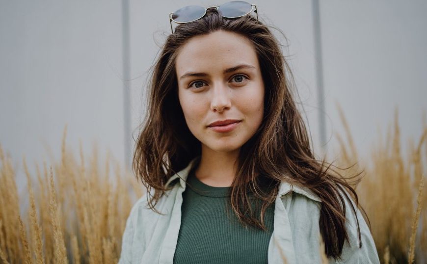 A woman wearing sunglasses in front of tall grass.