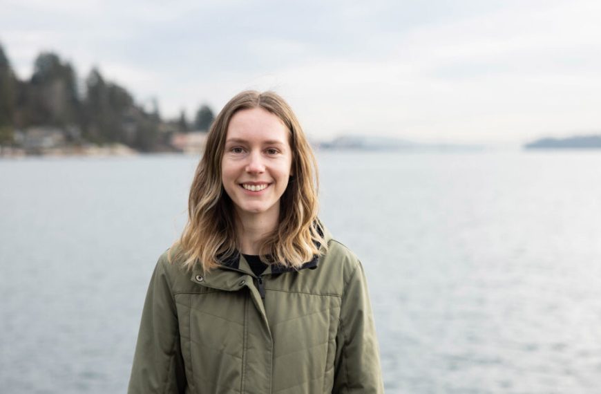 A young woman standing in front of a body of water.