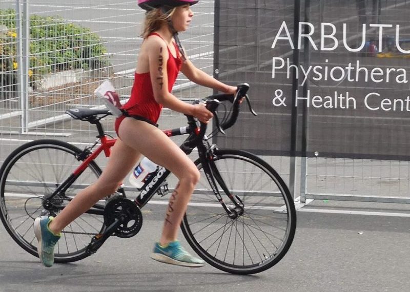 A young girl riding a bike in a bikini.