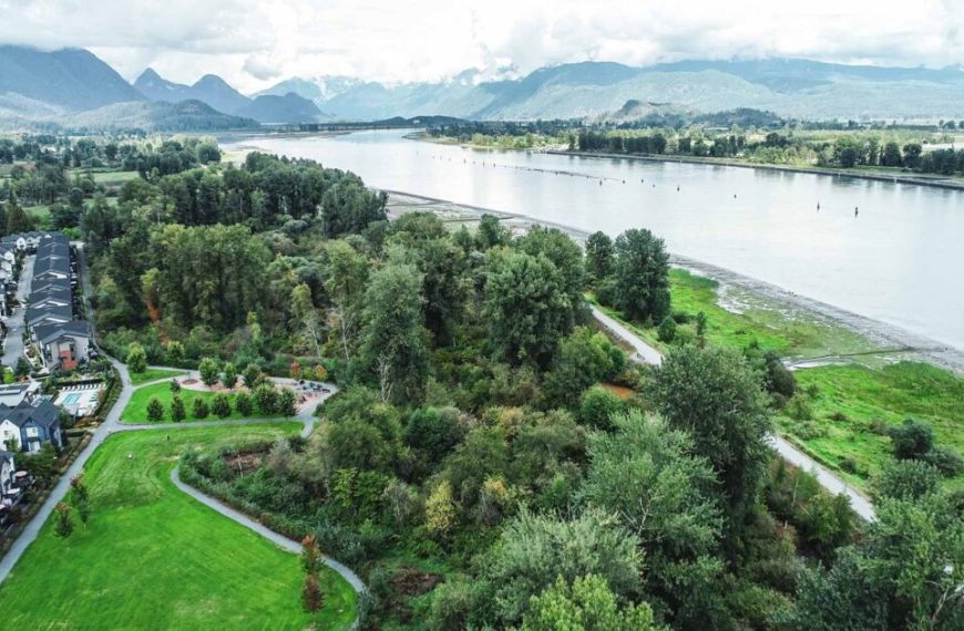 An aerial view of a residential area with a river and mountains.