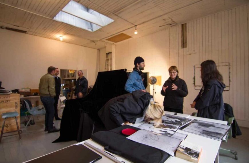 A group of people standing around a table in an art studio.