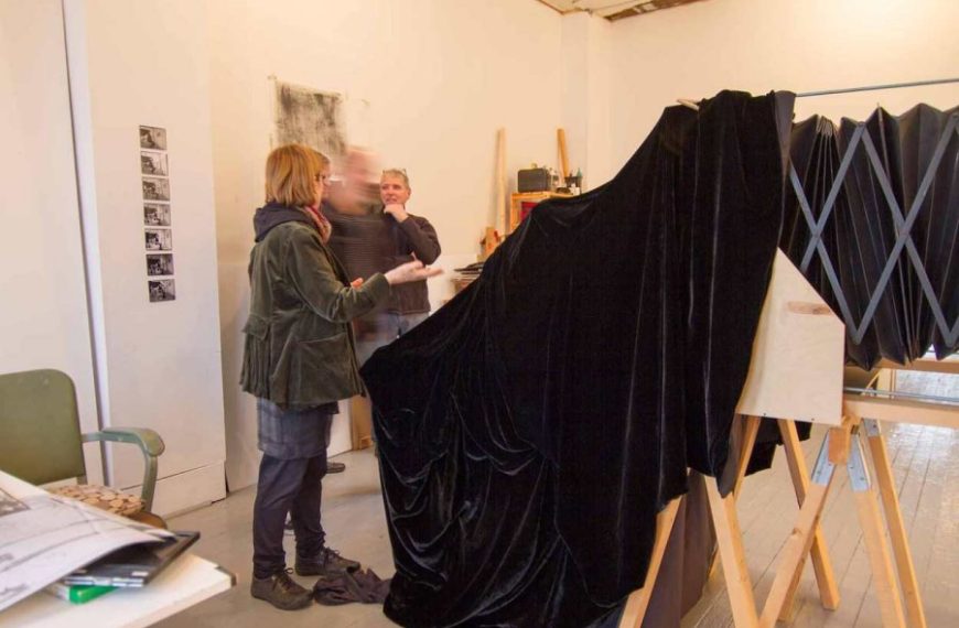 A group of people standing in front of an easel in an art studio.