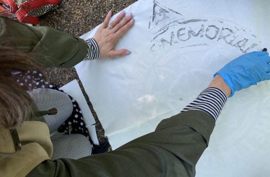A woman wearing gloves is writing on a piece of paper.