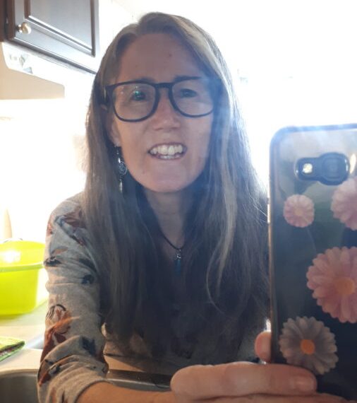 A woman taking a selfie in a kitchen sink.