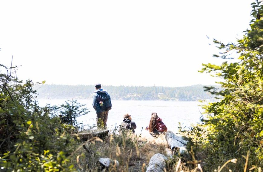 A group of people standing on a trail near a body of water.