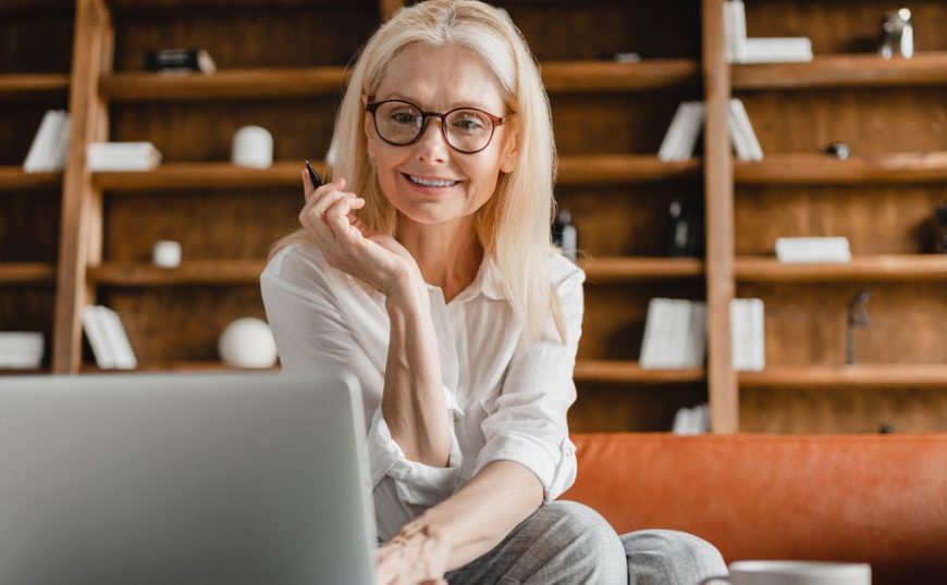 A woman sitting on a couch with a laptop and a cup of coffee.