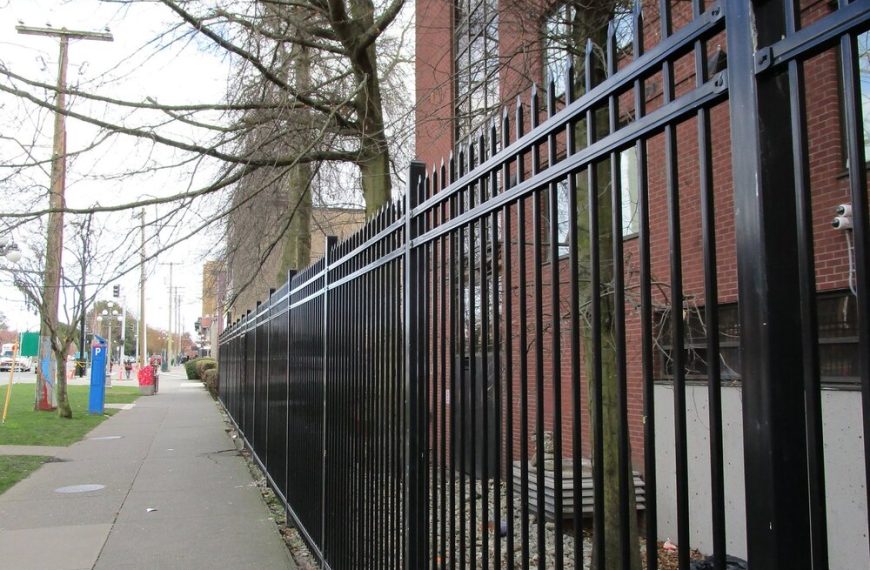 A black wrought iron fence on a sidewalk.