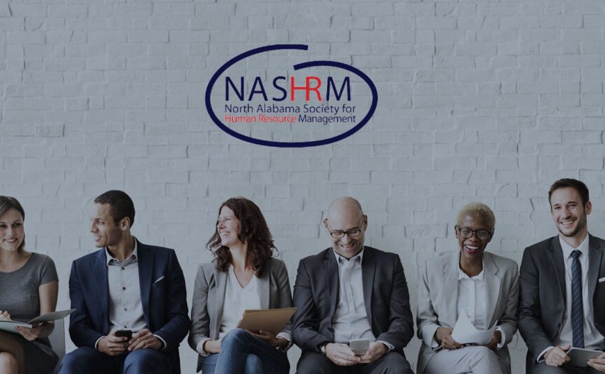 A group of people sitting in front of a brick wall with the words nasrm.