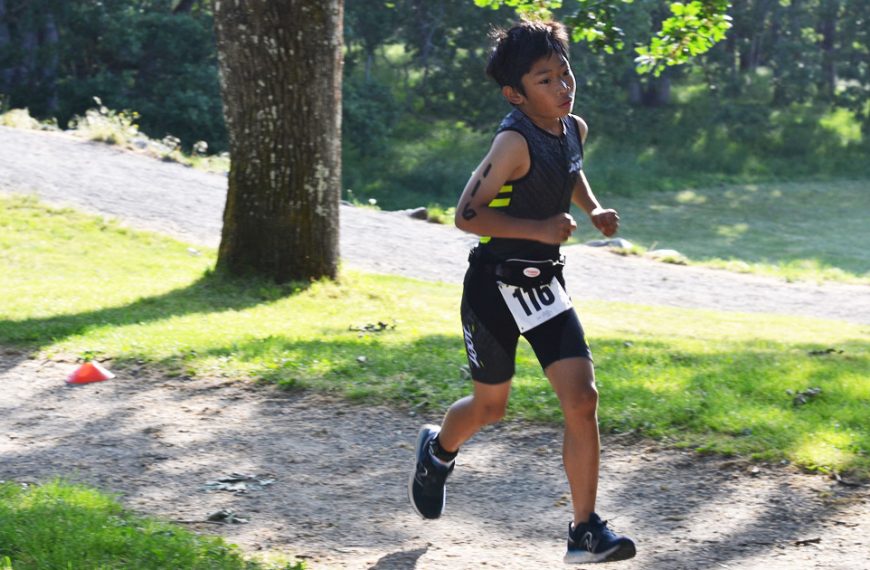 A young man running on a trail in a park.