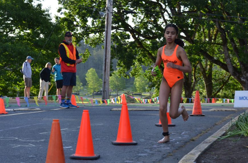 A girl in an orange bikini running through orange cones.
