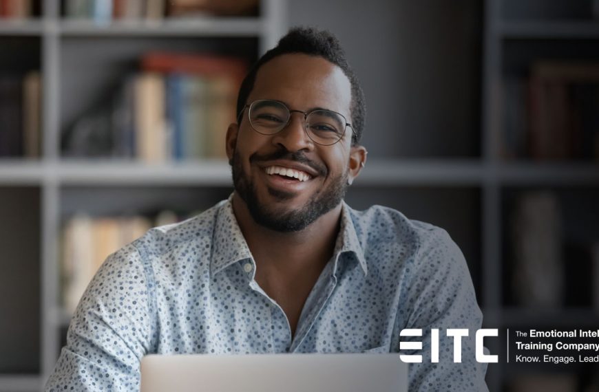 A man smiling in front of a laptop.