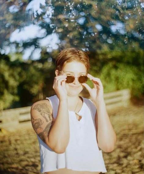 A woman wearing sunglasses in front of a tree.