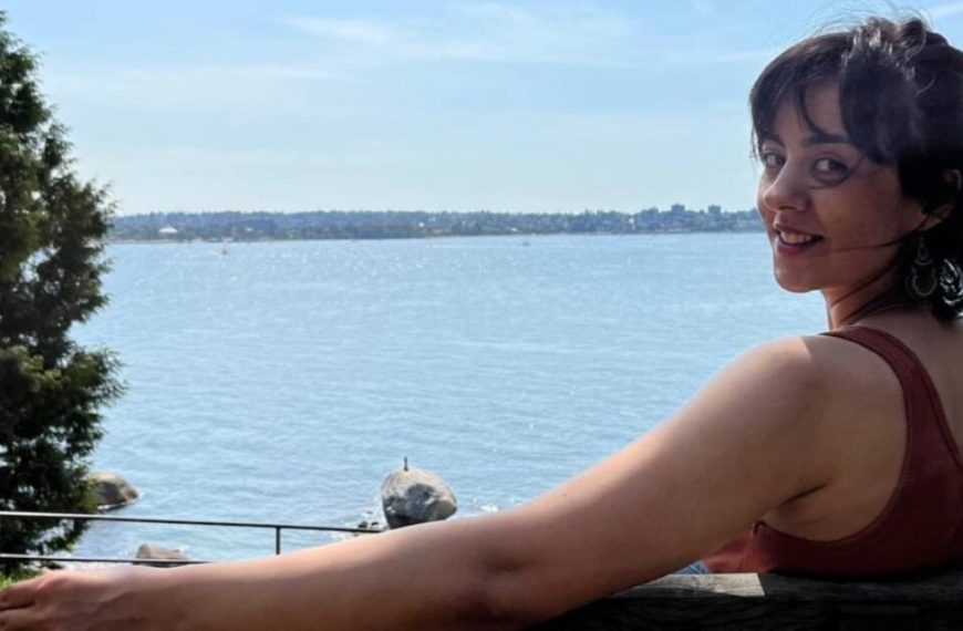 A woman leaning on a railing next to a body of water.