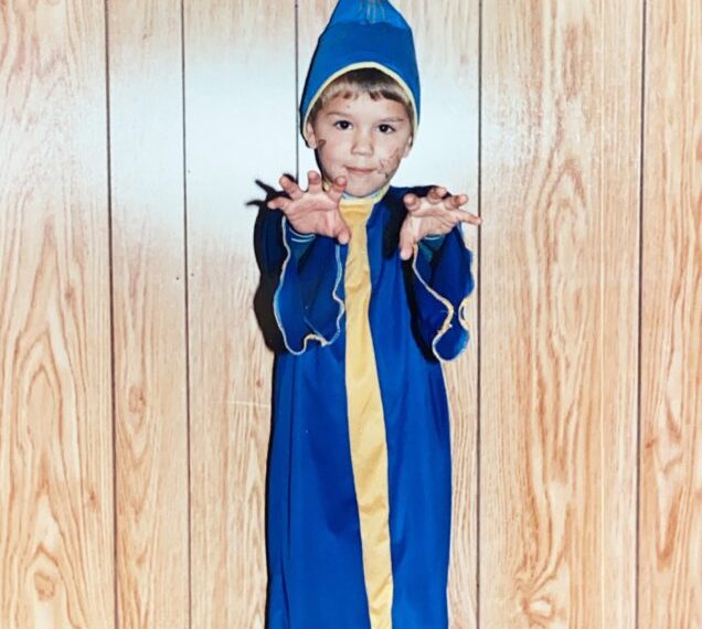 A young boy in a blue robe posing for a picture.