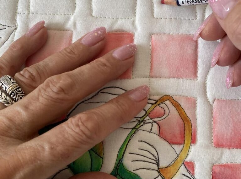 A woman is painting a quilt with watercolors.