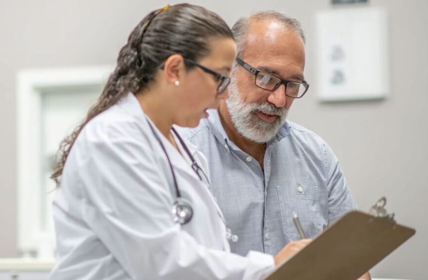 A doctor and a patient looking at a clipboard.