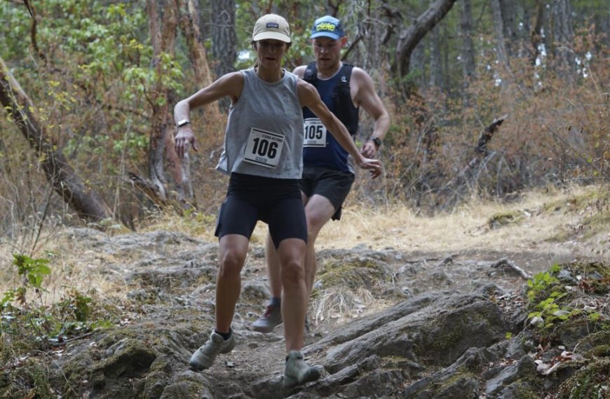 Two people running on a trail in the woods.