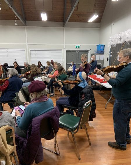 A group of people playing violins in a room.