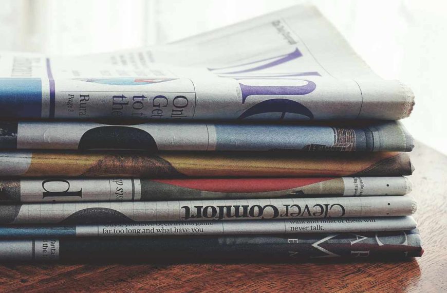 A stack of newspapers on a wooden table.