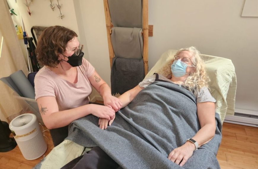 A woman wearing a mask is getting a massage in a room.