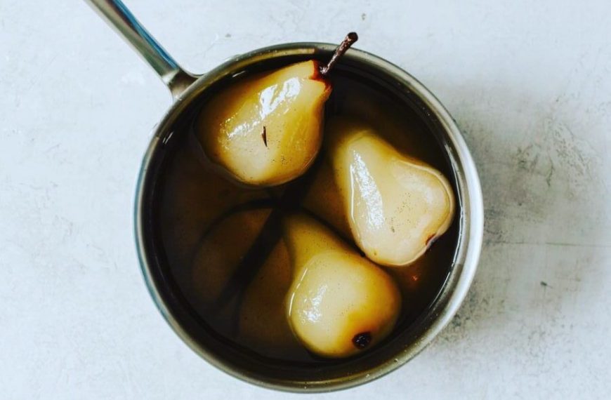 Pears in a pan with a spoon in it.