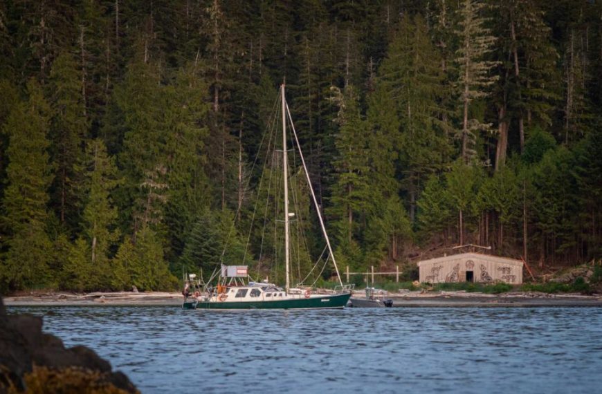 A sailboat docked in the water near a house.