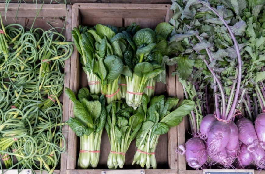 Fresh vegetables in wooden crates at a farmers' market.
