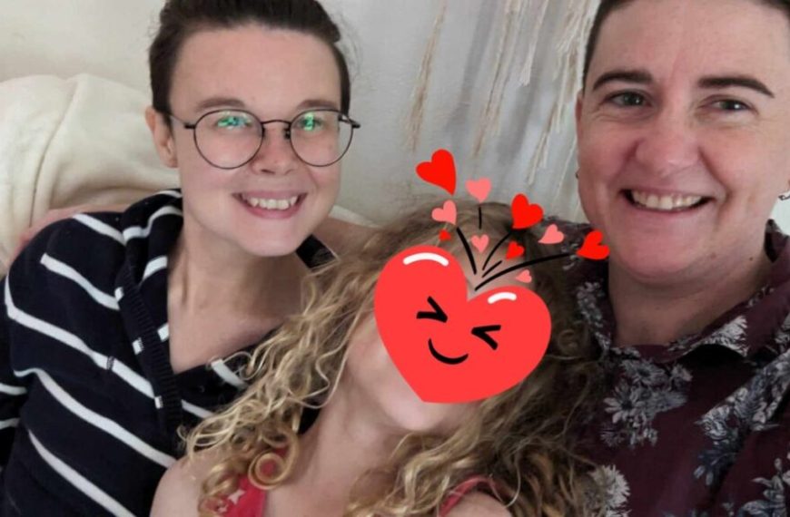 Three people are sitting on a couch with a heart shaped sticker on their faces.