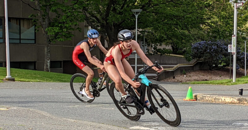 Two bicyclists are racing down a street.
