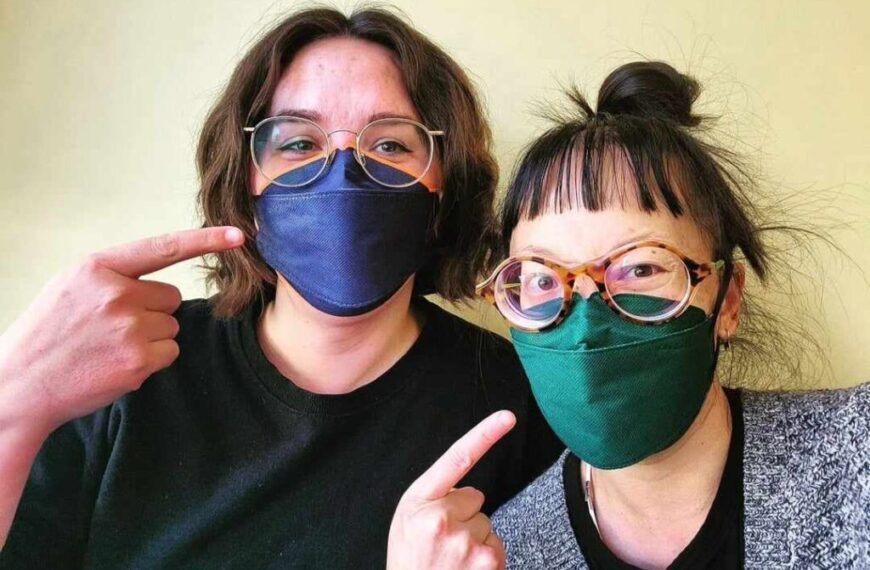 Two women posing for a photo wearing face masks as a reminder to practice proper masking.
