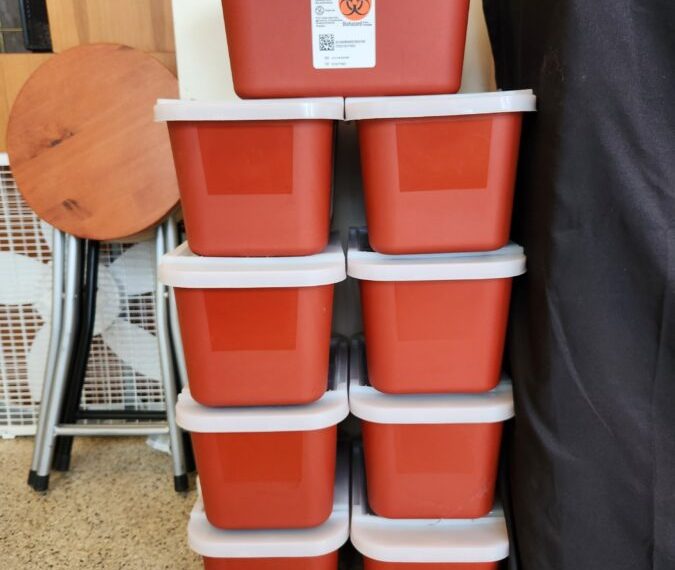 A stack of red plastic containers stacked on top of each other, resembling a pile of needles.